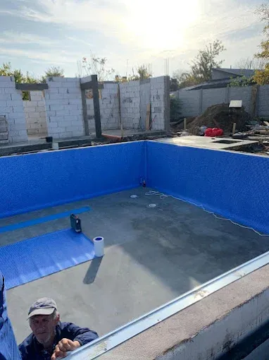 Montajul unui liner albastru cu model mozaic pe pereții unei piscine