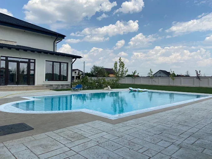 Piscină overflow în curtea unei case, cu apa la nivelul marginii